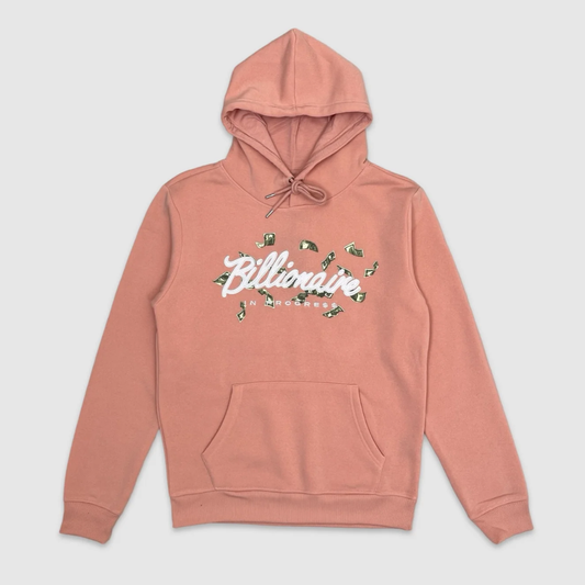 Pink hoodie with front graphic text embroidered 'Billionaire In Progress' surrounded by floating dollar bills.