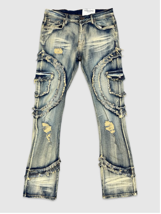 Men's distressed denim jeans with heavy frayed detailing, faded wash, ripped accents, and curved raw-hem patches – streetwear style.
